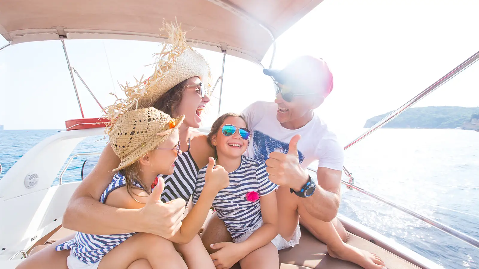 Bir teknenin güvertesinde birlikte vakit geçiren neşeli ve gülümseyen bir aile. Ailece yapılan tekne tatilini yansıtan mutlu bir an.